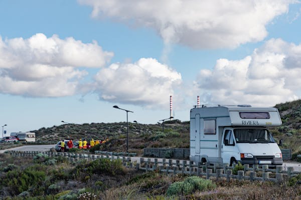 A Caravan Park where a few Caravan are parked and families are having picnic. 